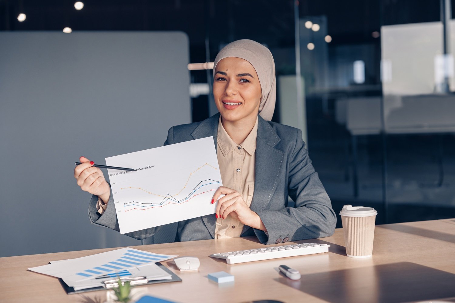 smiling muslim businesswoman in hijab shows a grap amh74w7.jpg